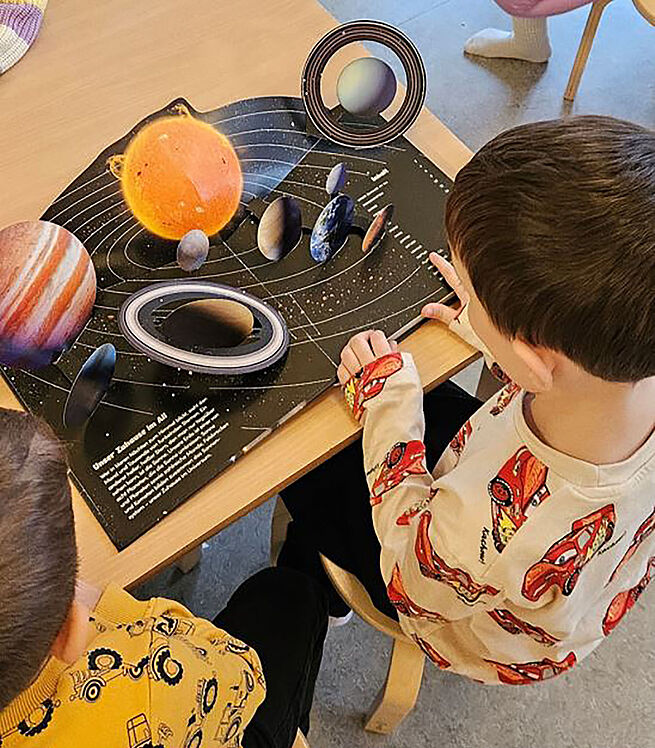 Kind schaut Buch über Weltraum an