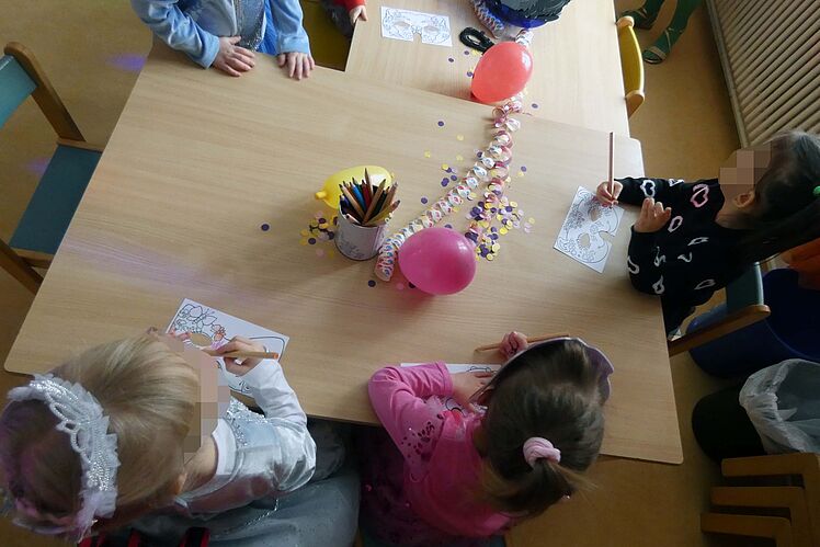 verkleidete Kinder am Tisch basteln Masken