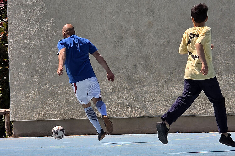 Ein Erzieher und ein Kind beim Fußball spielen