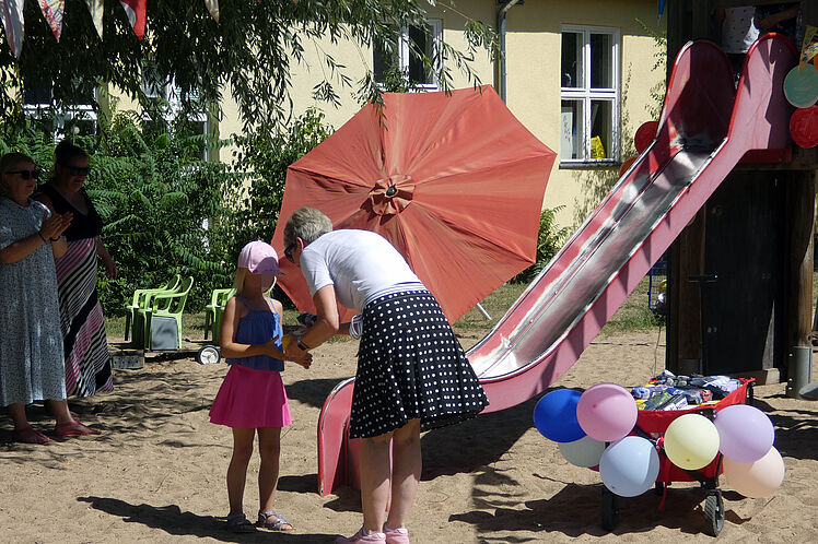 Kind bekommt von stellvertretender Kita-Leiterin Federmäppchen überreicht