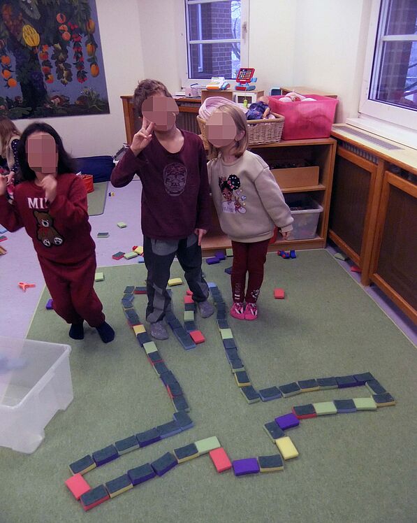 Kinder betrachtet eine Körperumrandung aus kleinen Schwämmen vor sich auf dem Boden.