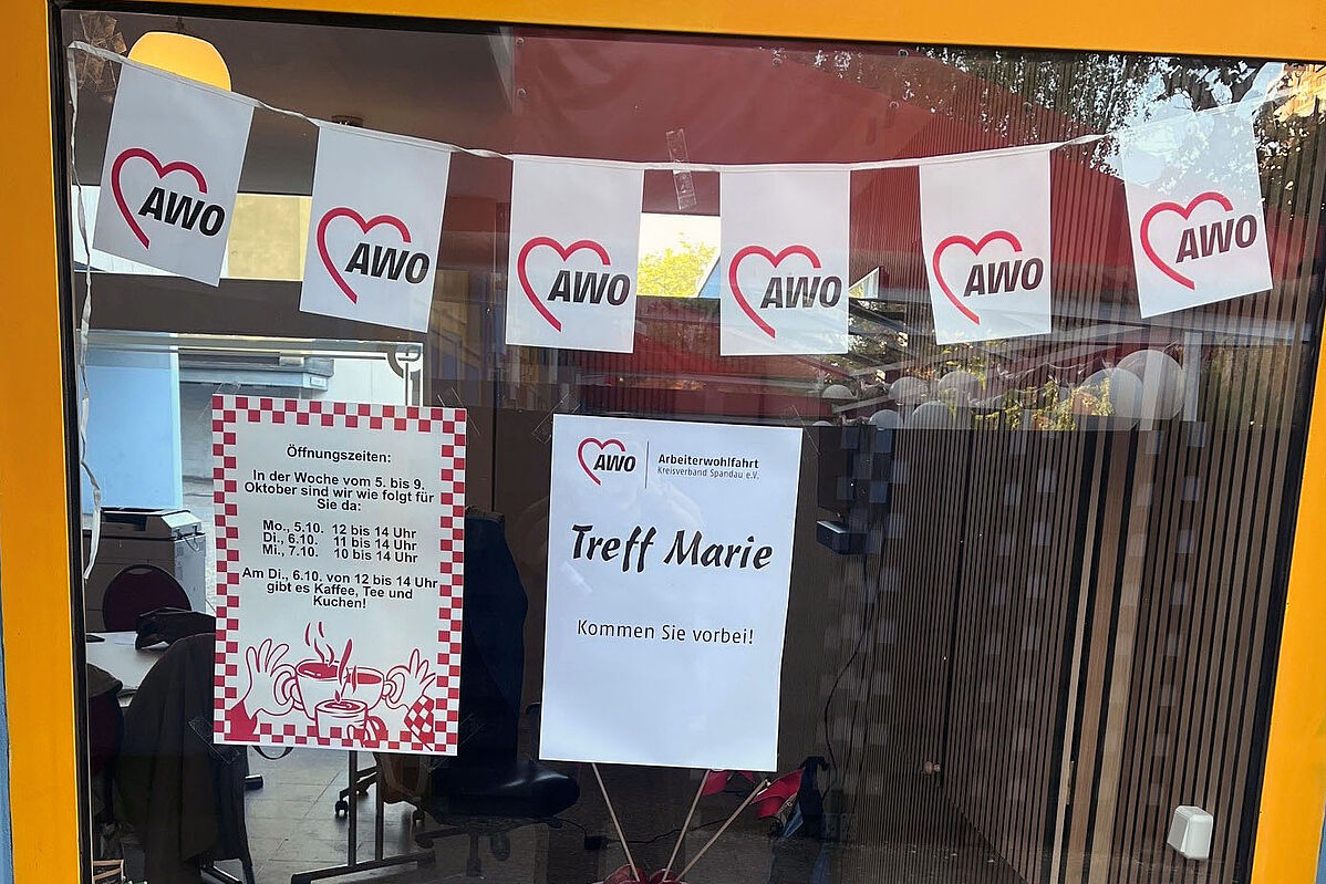 Eingangstür zum Treff Marie mit AWO-Fahnenkette und zwei Aushängen