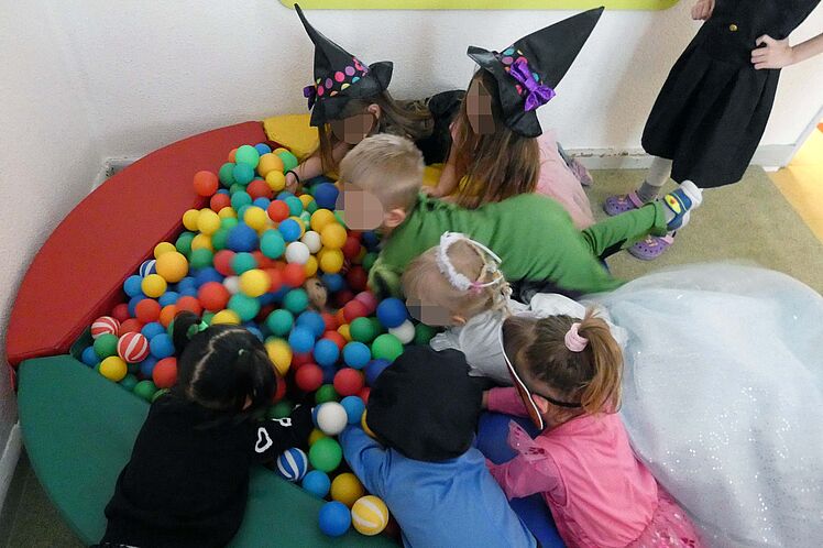 verkleidete Kinder liegen auf dem Bällebad