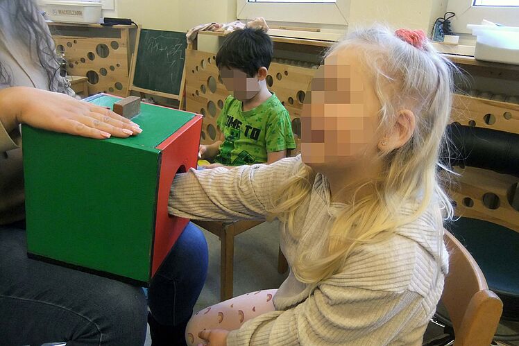 Blondes Kind steckt Hand in Kasten, um Formen zu ertasten