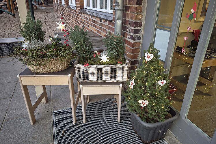 Weihnachtliche Gestecke und Bäumchen vor der Kita