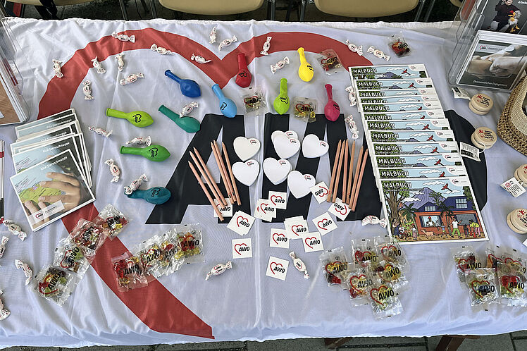 Nahaufnahme des mit Werbemitteln wie Gummibärchen, Malbüchern und Herzchen-Klebezetteln geschmückten AWO-Stands