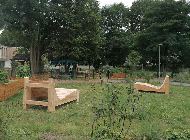 zwei Wellenliegen aus Holz im Garten des Horts