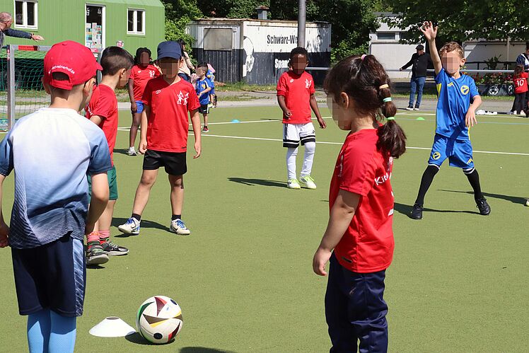 Kinder überwiegend in roten Trikots spielen Fußball