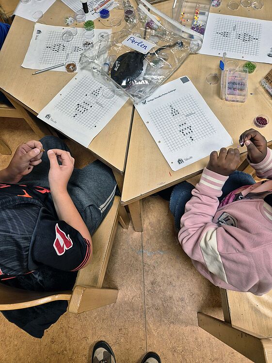 Kinder am Basteltisch mit Perlen 