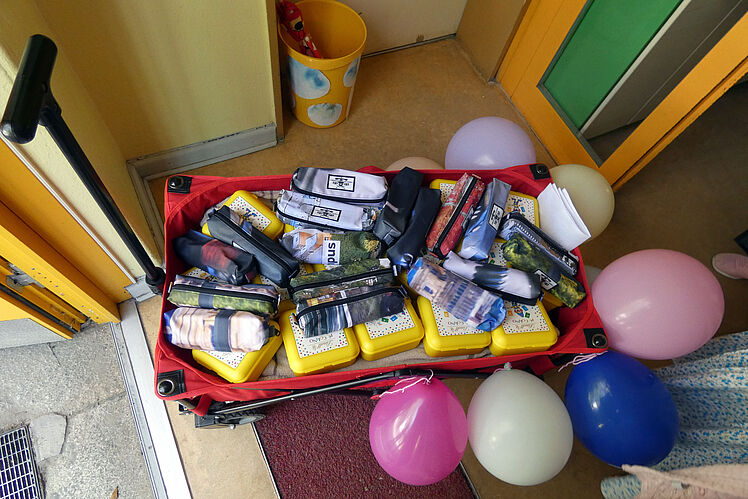Bollerwagen gefüllt mit gespendeten Federmäppchen, verziert mit Luftballons