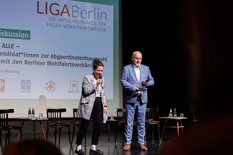 Moderatorin Anke Myrrhe und AWO-Berlin Vorsitzender Oliver Bürgel stehen zu Beginn nebeneinander auf der Bühne