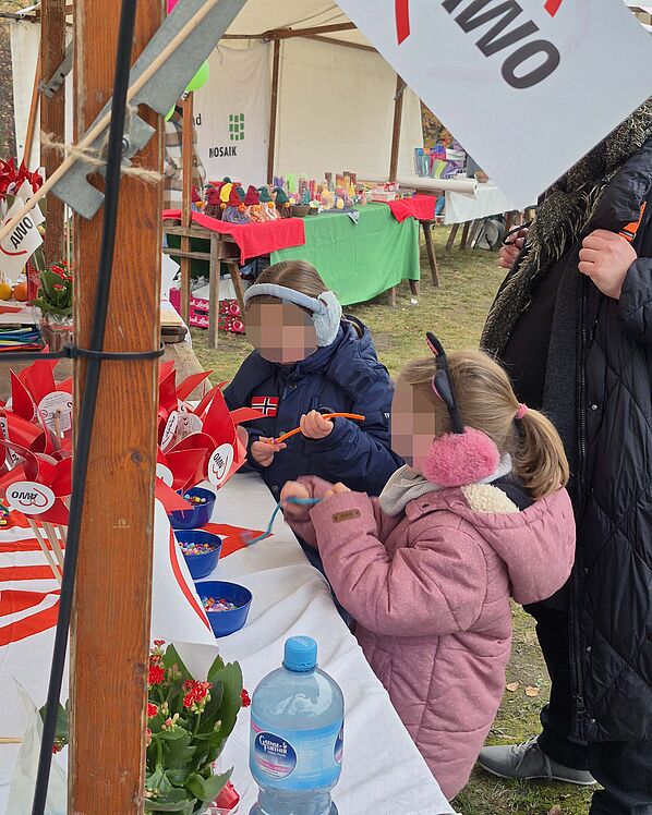 Kinder am AWO-Stand beim Perlenfädeln