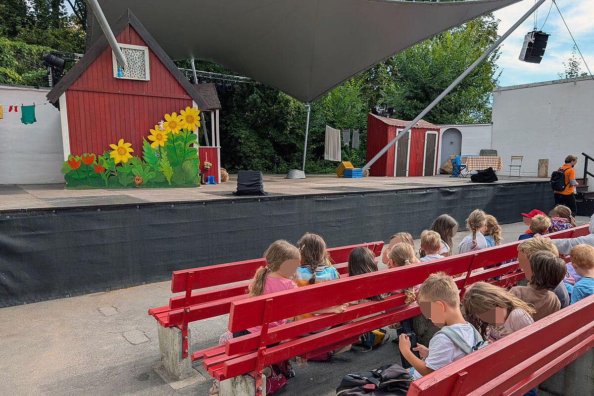 Kinder seitlich von hinten in den Sitzreihen vor der Freilichtbühne