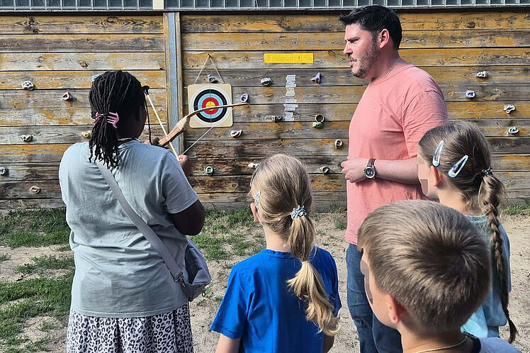Erwachsene und Kinder beim Bogenschießen