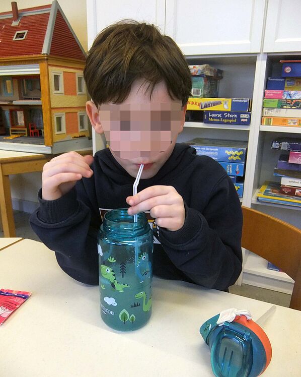 Kind trinkt mit Trinkhalm aus einer Plastik-Trinkflasche.