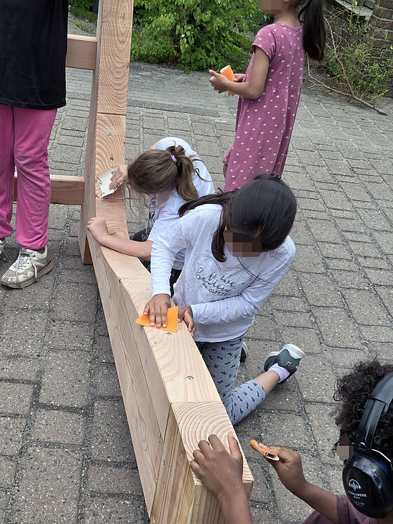 Kinder schleifen Holzbalken ab