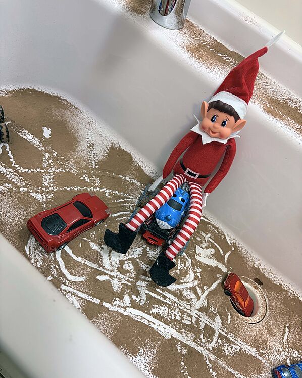 Wichtel mit Spielzeugautos und Sand im Waschbecken